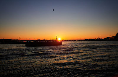 View of sea harbor against sky during sunrise