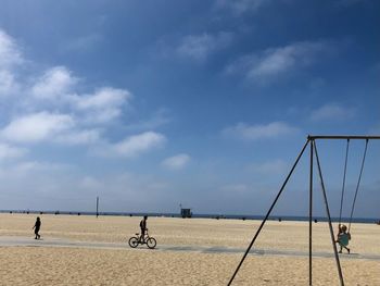 People riding bicycle on land against sky