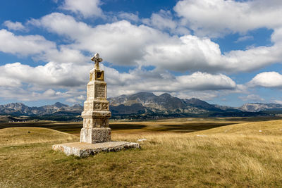 Built structure on landscape against cloudy sky