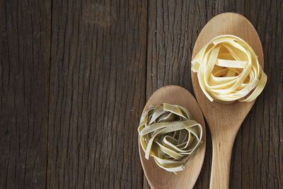 Close-up of tagliatelle pasta in wooden spoons on table