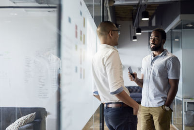 Businessmen discussing while standing at corridor in office