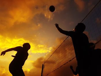 Low angle view of silhouette man playing with ball against sky during sunset