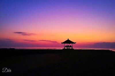 Silhouette of lifeguard hut on beach during sunset