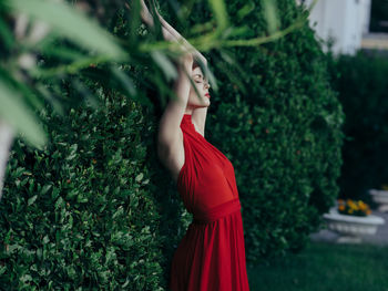 Side view of young woman standing by plants