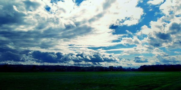 Scenic view of grassy field against cloudy sky