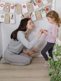 Mother with child opening christmas advent calendar tasks and gifts. toddler girl excited about