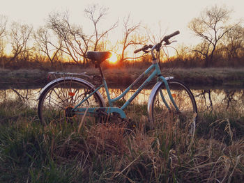 Bicycle on field against sky during sunset