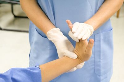 Midsection of doctor bending patient hand