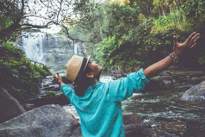 Midsection of man standing on rock in forest