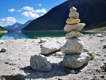 Stack of stones on shore against sky