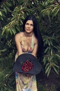 Portrait of a young woman standing against plants