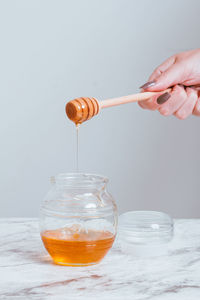 Cropped hand of person pouring into glass on table