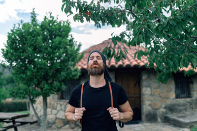 Young man standing against trees