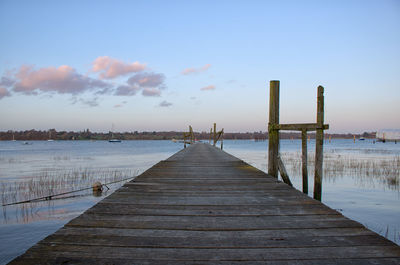 Wooden jetty on pier at lake against sky