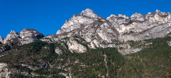 Low angle view of rocky mountains against clear blue sky