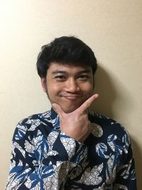 Portrait of young man standing against wall