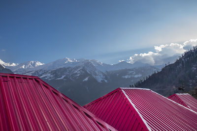 Snow mountain with nice sun rays and clouds and red roof of house.