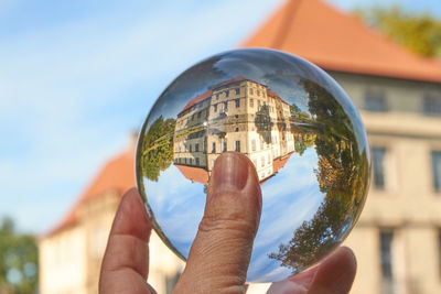 Close-up of hand holding glass of building