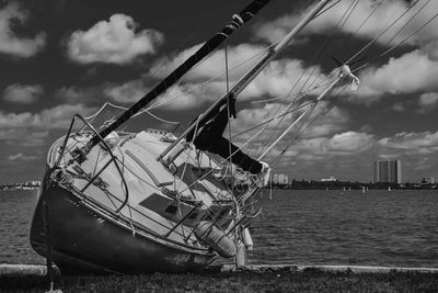 Low angle view of boat in calm sea against clouds