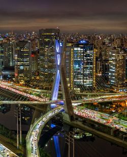 Aerial view of illuminated bridge and buildings in city at night