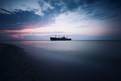 Silhouette ship on sea against sky during sunset