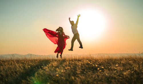 Woman standing on field against sky during sunset