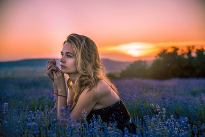 Beautiful woman standing on field against sky during sunset