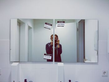 Young man clicking himself with camera phone at the mirror