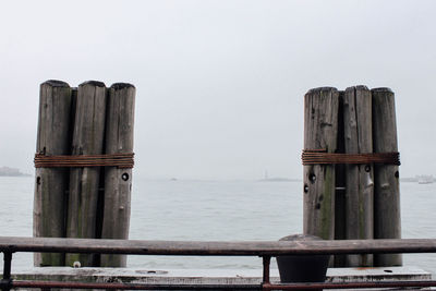 Wooden post on pier over sea against sky