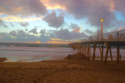 Pier on sea against cloudy sky