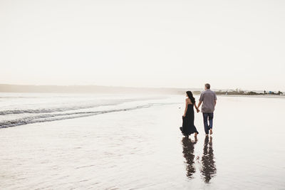 Romantic couple holding hands walking in the surf