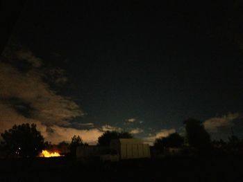 Silhouette trees and buildings against sky at night