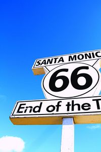 Low angle view of sign board against clear blue sky