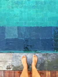 Low section of man standing by swimming pool