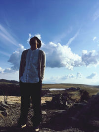 Man standing on rock against sky