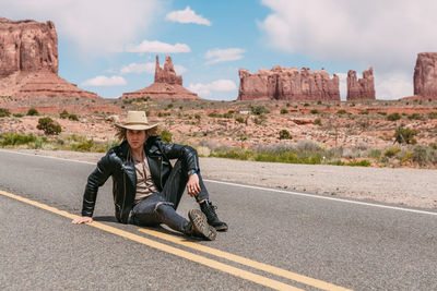 Man sitting on rock against road