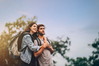 Young couple standing against sky