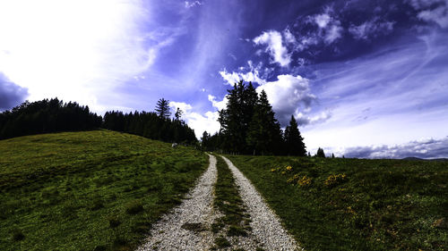 Scenic view of road amidst field against sky