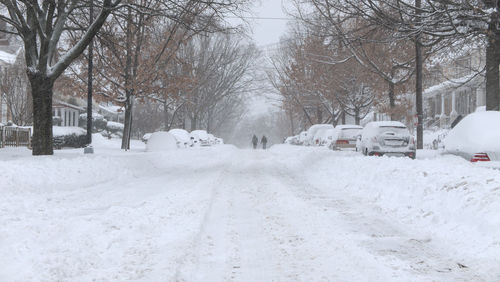 Couple walking in the snow at the distance, streets of north west washington dc under blizzard, usa