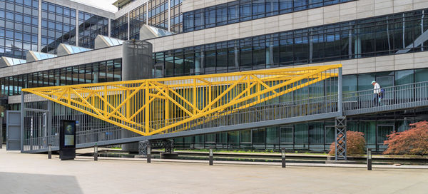 People on bridge against modern buildings in city