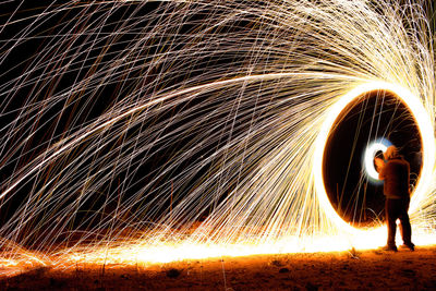 Rear view of man spinning wire wool at night