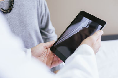 Close-up of doctor explaining x-ray image to patient on tablet computer