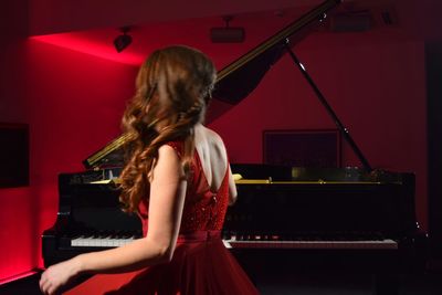 Side view of musician playing piano on stage in theater