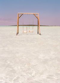 Empty swings at sea against sky