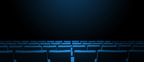 Empty chairs in row against black background