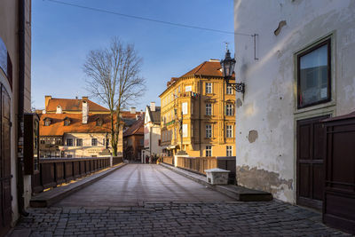 Wooden bridge and footpath with residential buildings against sky