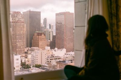 Woman looking at cityscape through window