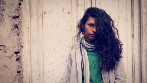 Portrait of young woman standing against door