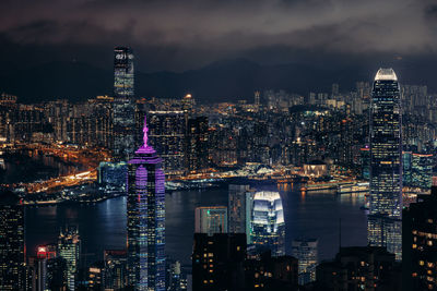 Illuminated modern buildings in city against sky at night