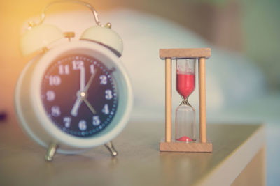 Close-up of hourglass and alarm clock on table